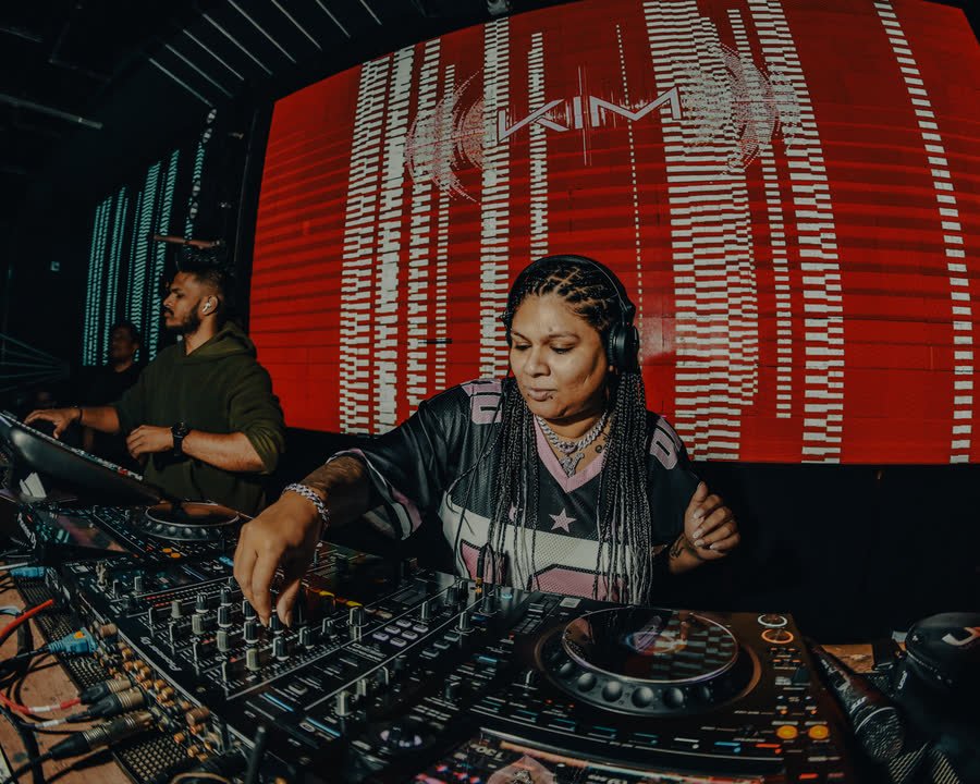 DJ Kim at the CDJs in front of a red LED wall