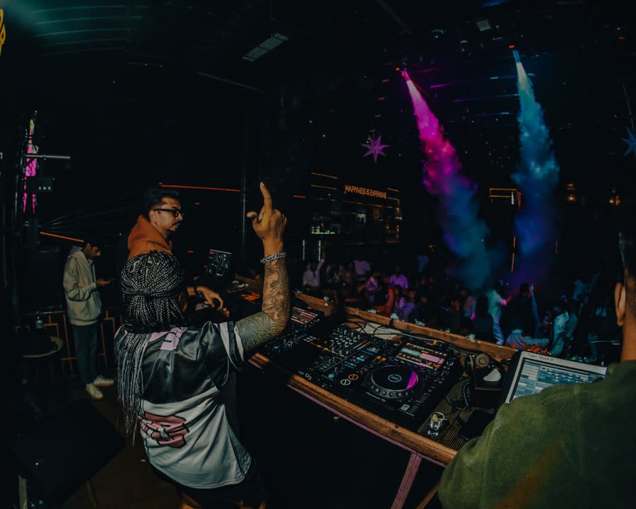 The dancefloor seen from the DJ booth, beams and coloured haze over the crowd