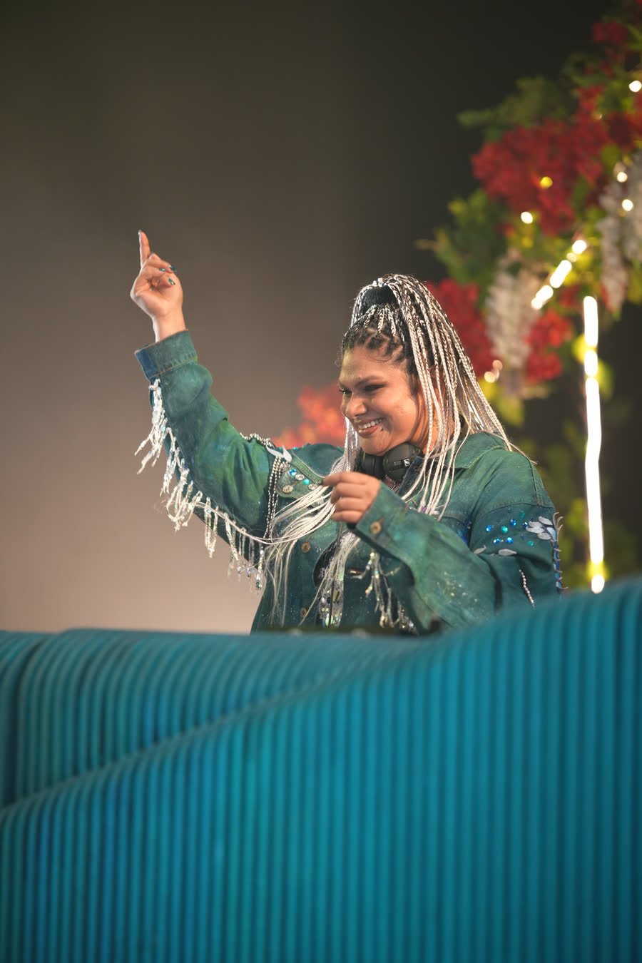 DJ Kim on the microphone at an open-air set, one hand raised