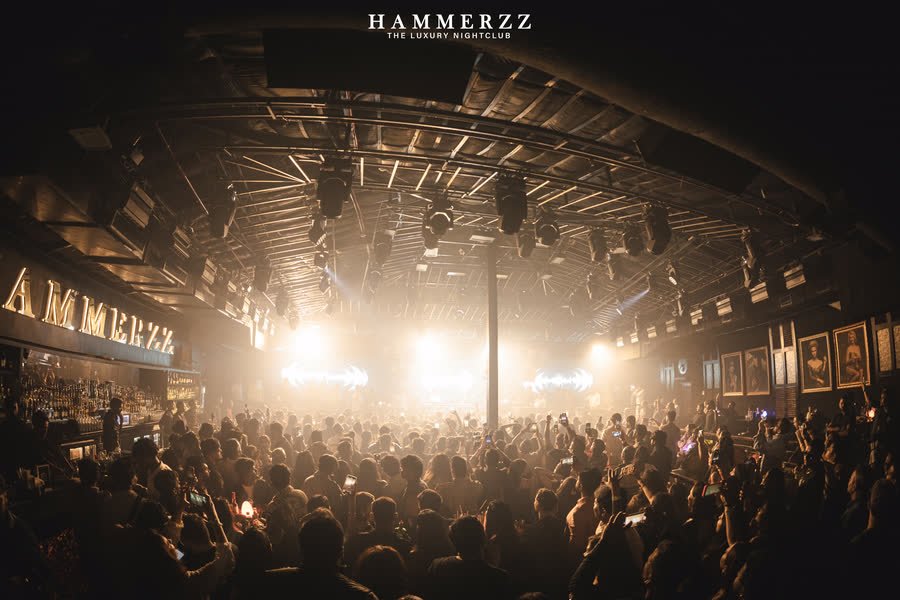 Wide view of a packed room, beams cutting through haze