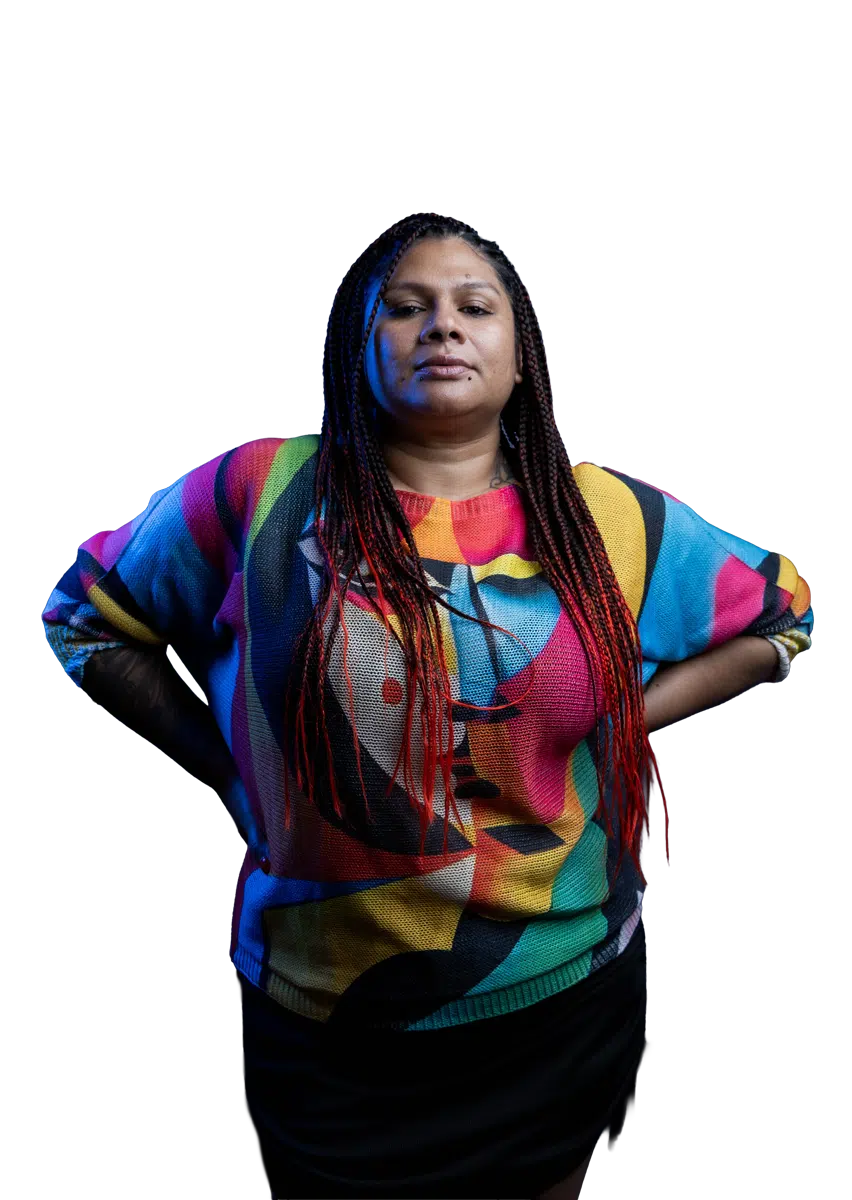DJ Kim posing in a bright multicoloured top against a dark background