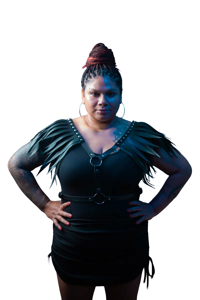 DJ Kim standing with hands on hips in a black studio portrait