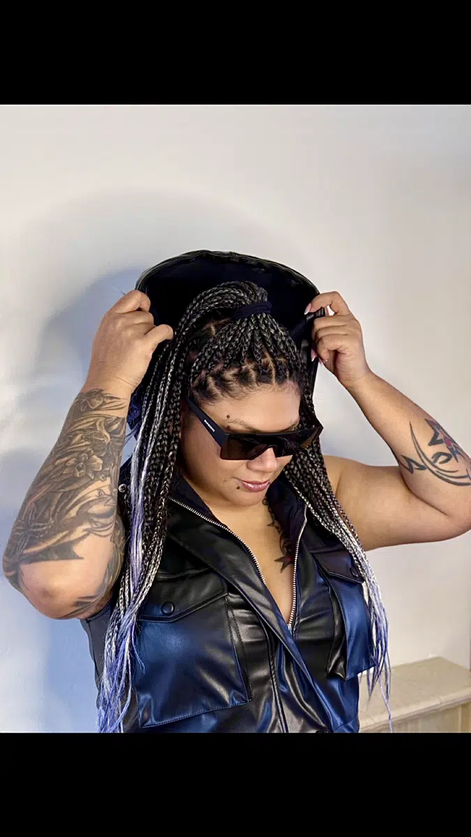 DJ Kim adjusting headphones while wearing sunglasses and black leather