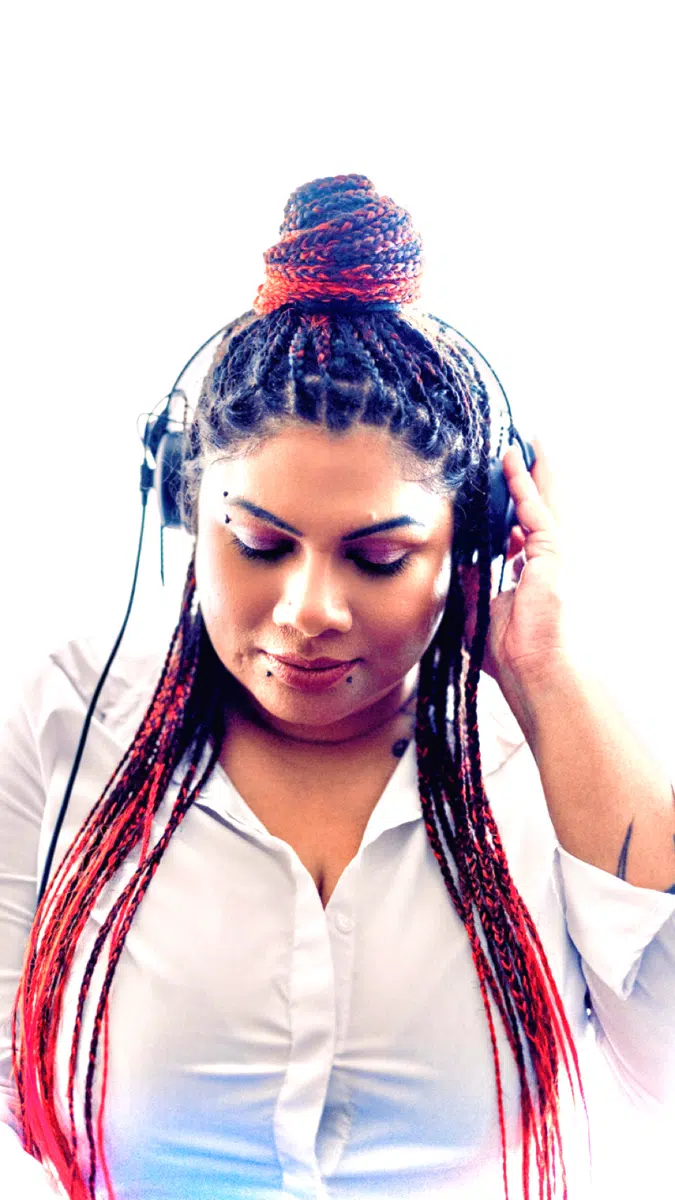 DJ Kim looking down with headphones on in a white shirt portrait
